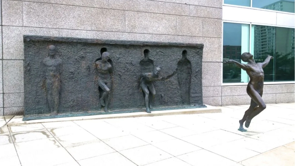 Skulptur som symboliserar frihet – figurer som bryter sig ur en vägg